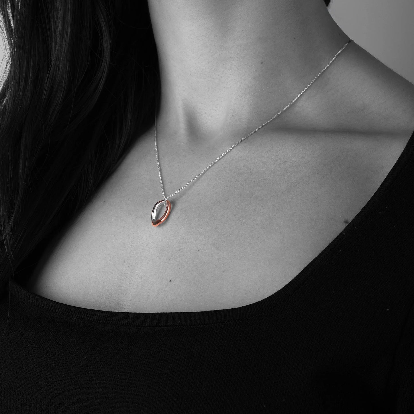 Copper and silver Necklace with a unique pendant worn by a person against a dark background