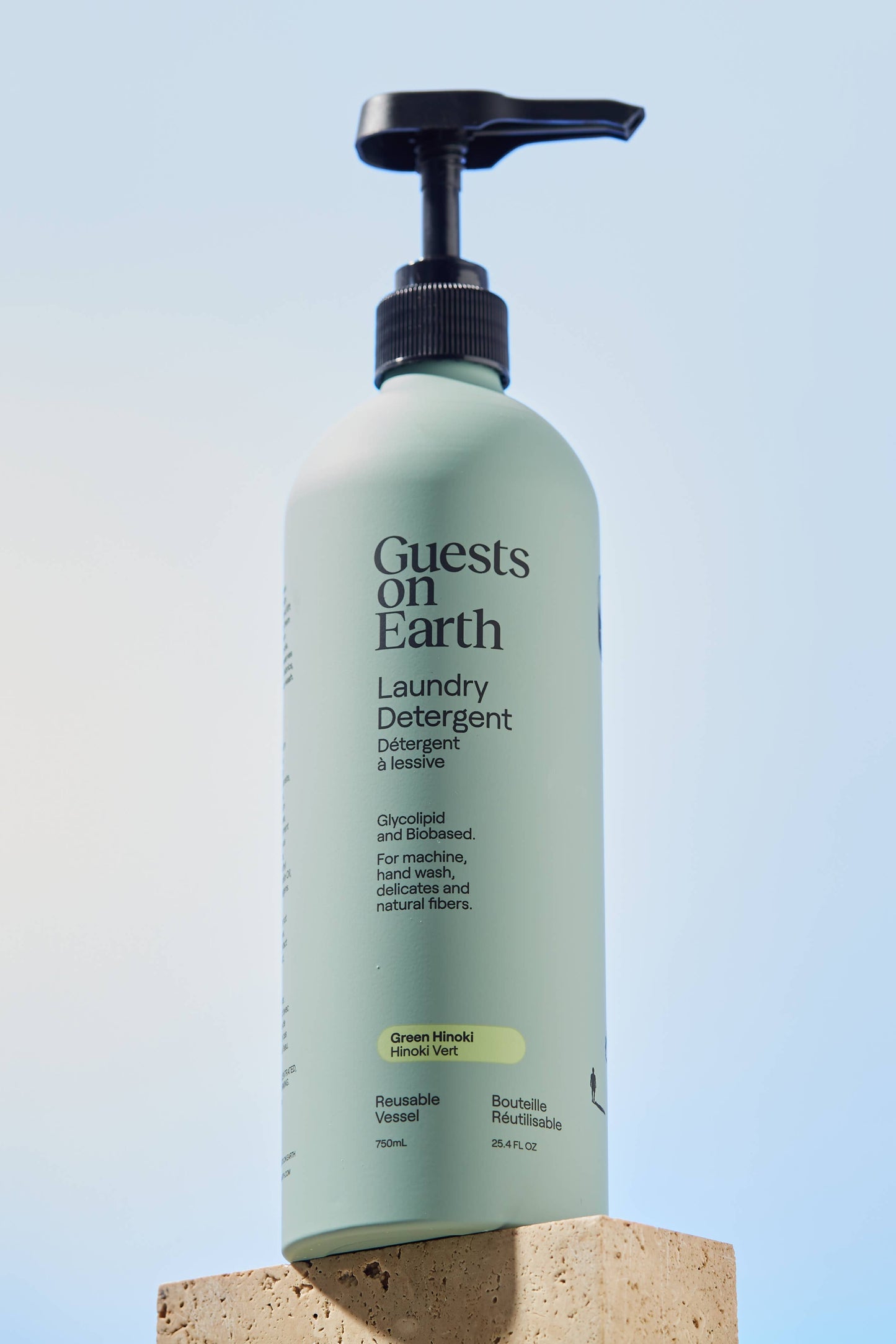 Bottle of Guests on Earth laundry detergent against a light blue background