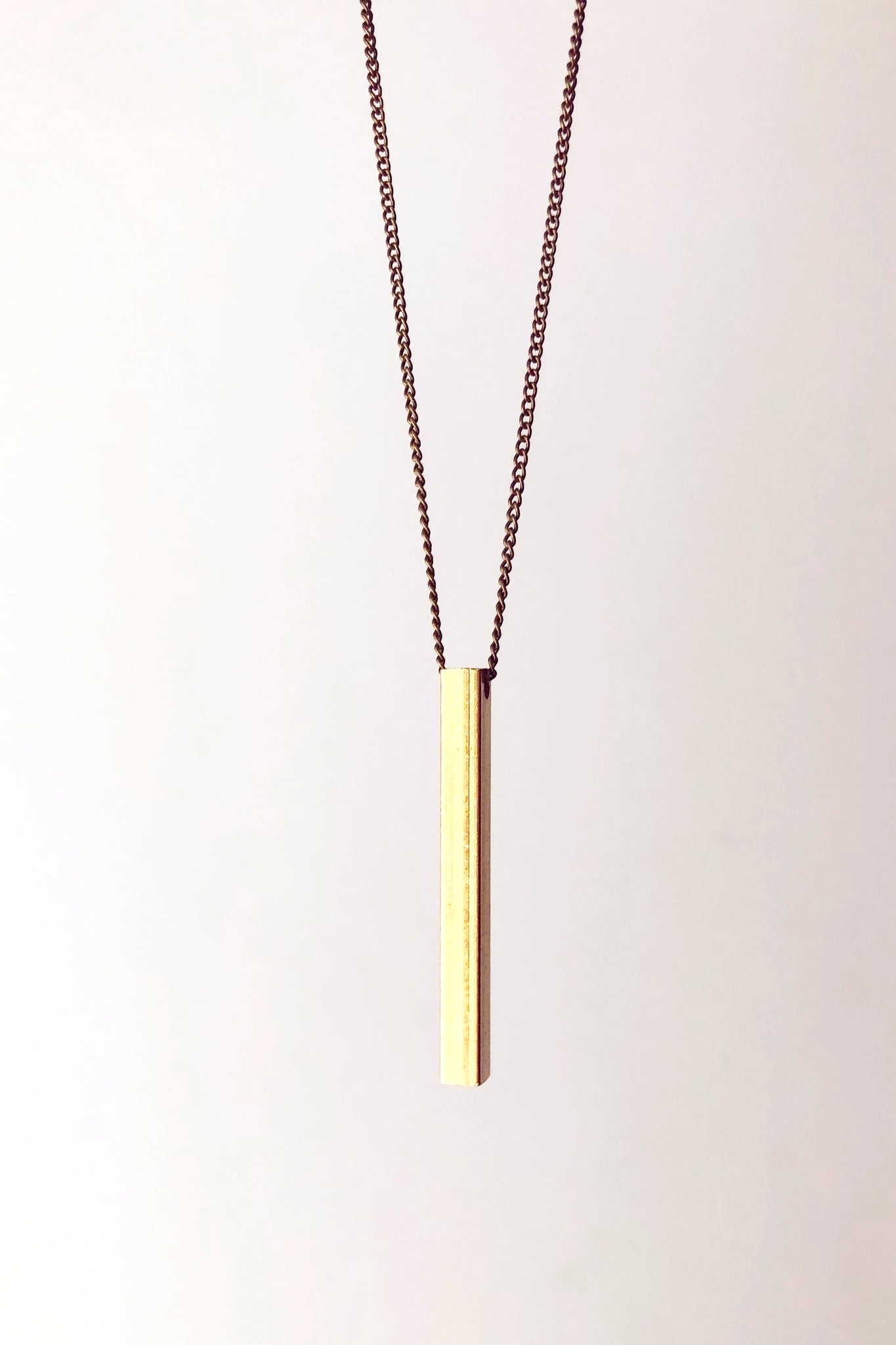 Beatrice necklace by Darlings of Denmark; mid-length chain; raw brass; vertical solid bar detail; close-up; flat lay
