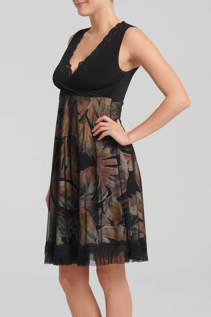 Levana Dress by Kollontai, side view, black top with wrap-over neckline and lace trim, sleeveless, empire waist, A-line skirt with tropical print under a black mesh layer, ruffled hem, knee length, sizes XS to XXL, made in Quebec