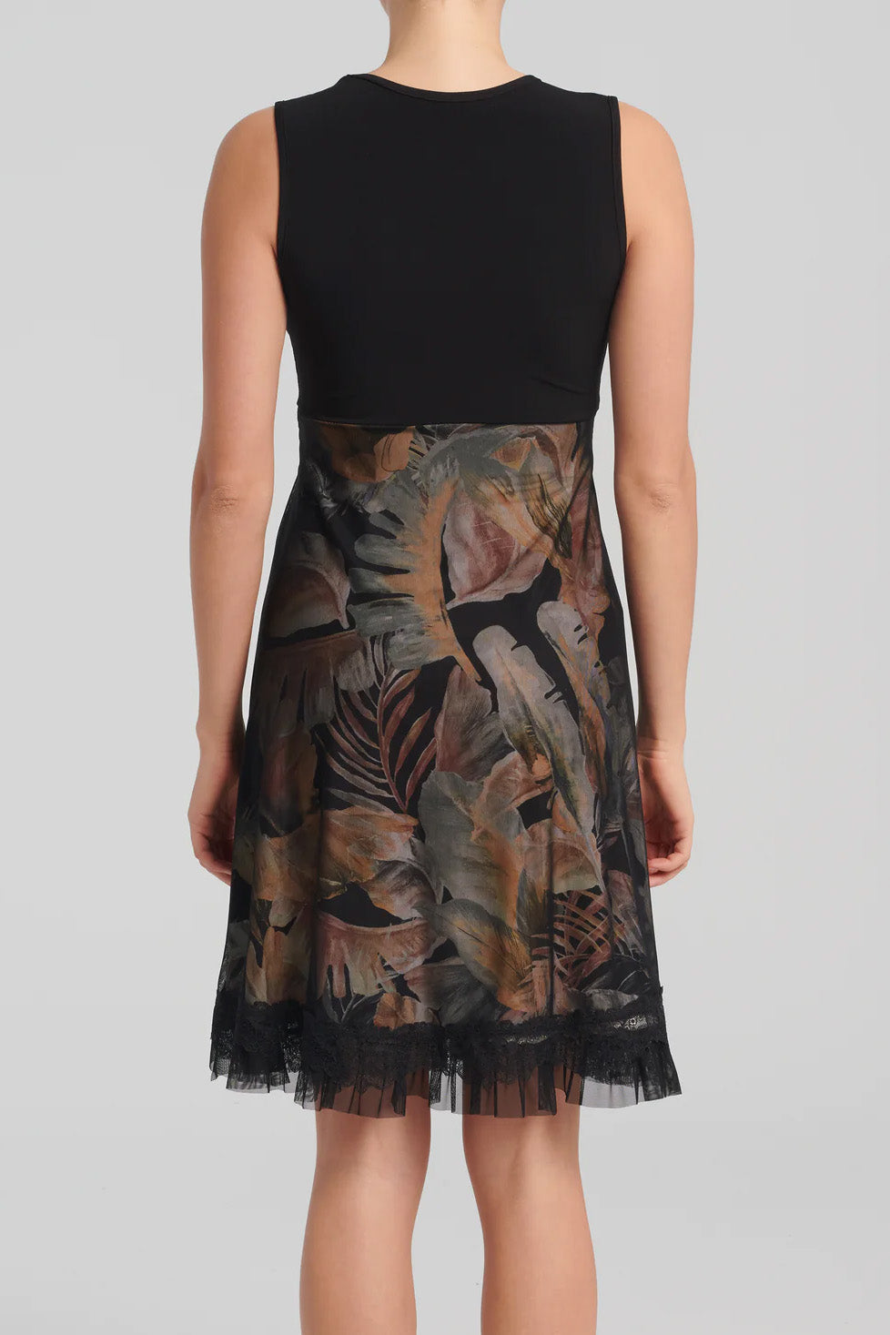 Levana Dress by Kollontai, back view, black top with wrap-over neckline and lace trim, sleeveless, empire waist, A-line skirt with tropical print under a black mesh layer, ruffled hem, knee length, sizes XS to XXL, made in Quebec