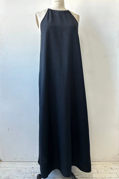 The Anwen Dress by Kollontai in Black, a loose-fitting rayon maxi dress with an adjustable halter neckline, is shown on a mannequin in front of a white background. 