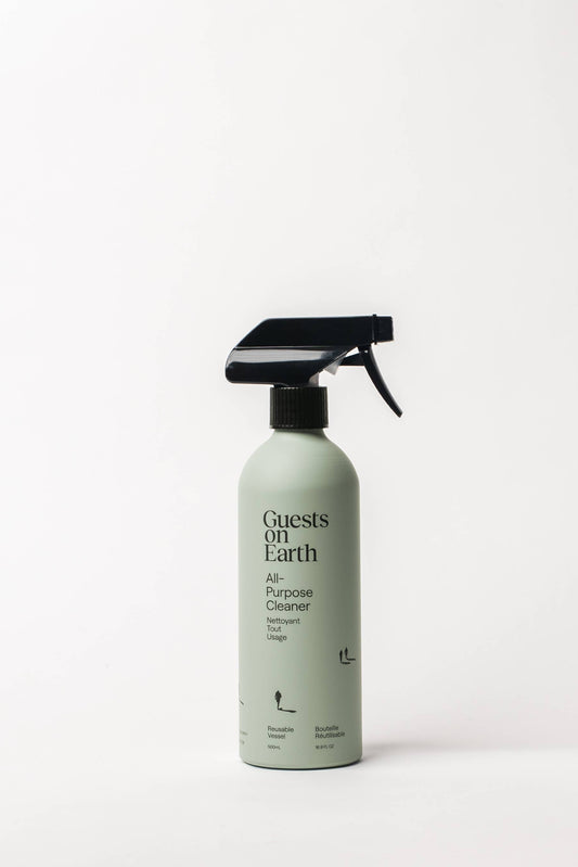 A spray bottle of Guests on Earth All Purpose Cleaner in Woodlands is shown on a white background