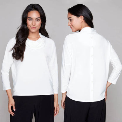 Side by side back and front views  woman wearing the Perry Top by Compli K in Ivory, featuring a cowl neck, 3/4 drop sleeves, and decorative buttons up the back. She is wearing it with black pants and standing in front of a white background. 