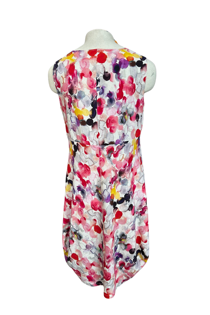 A back view of the Monica Dress by Solomia in Watercolour Print is shown on a mannequin against a white background. It's a sleeveless knee-length dress with a relaxed fit and uniquely angled bottom hem. 