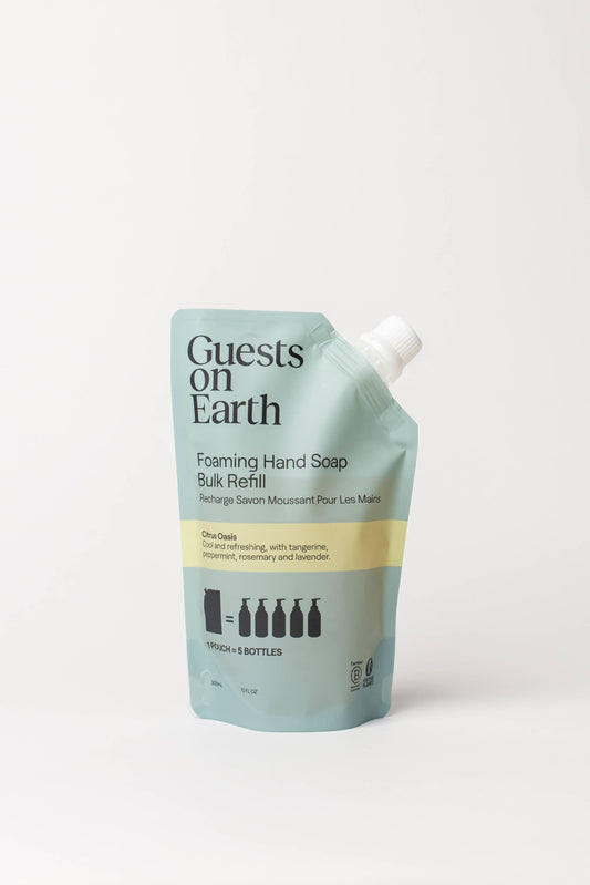 Guests on Earth Foaming Hand Soap Bulk Refill refill pouch in a light blue-green color with a yellow stripe and white cap, on a clean white background.