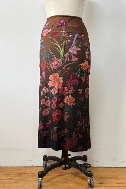 The Charlotte SKirt by Kollontai, a long slim cut brown skirt adorned with a floral pattern, is shown on a mannequin against a white background. 