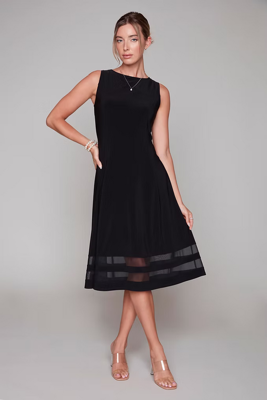 A woman wearing the Rowena Dress by Compli K, a sleeveless black dress with a cocktail length hem with sheer bands across it. 