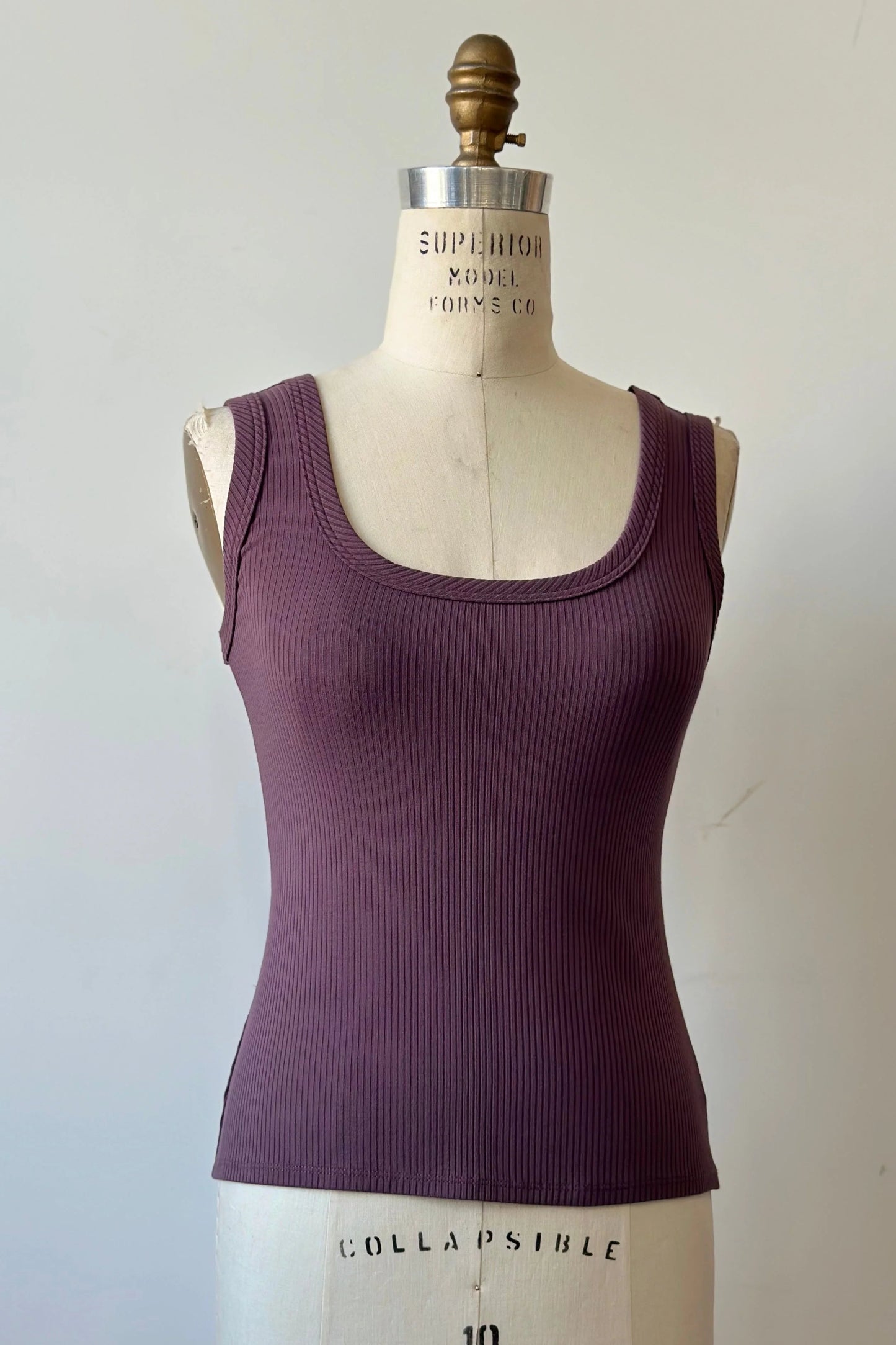 The Rina Camisole from Kollontai, a ribbed tank in stretchy bamboo with side straps and a scooped neck front and back, is shown on a mannequin in front of a white background. 