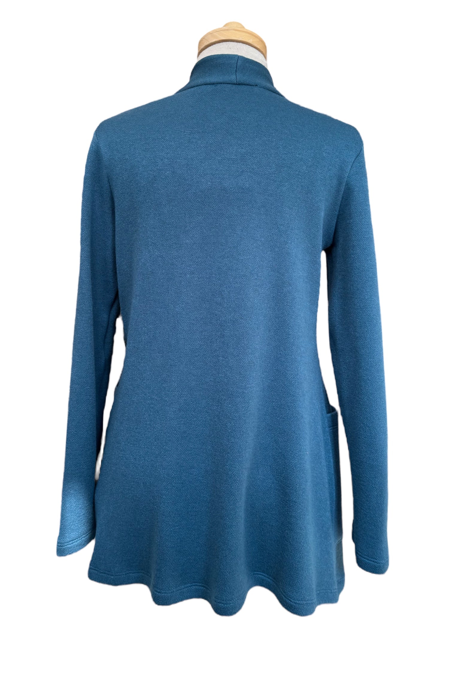 A back view of the Penny Cardigan by Compli K in Peacock, a long open knit cardigan with long sleeves and large patch pockets, is shown on a mannequin against a white background.