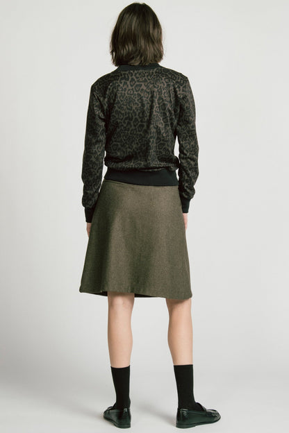 Back view of a woman wearing the Crux Sweatshirt by Allison Wonderland in Animal Print. she is wearing it with a grey skirt and standing in front of a white background. 