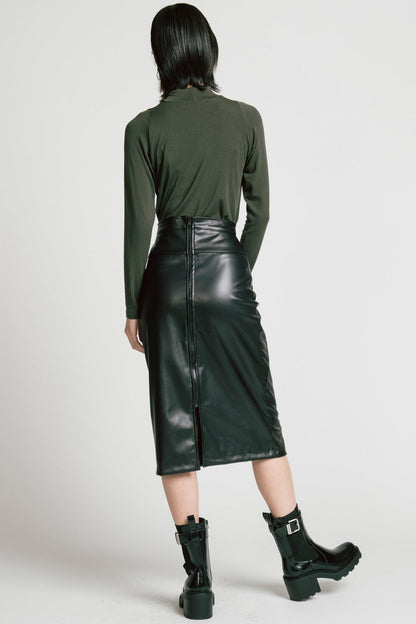Back view of a  woman wearing the Aches Turtleneck by Allison Wonderland in Green, a slim fitting classic turtleneck. She is wearing it with the Desire Skirt in Black and standing in front of a white background. 