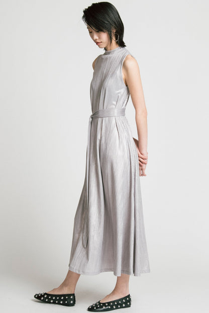 Side view of a woman wearing the Swing Dress by Allison Wonderland in Silver, a sleeveless mock neck maxi dress in shimmery fabric. 