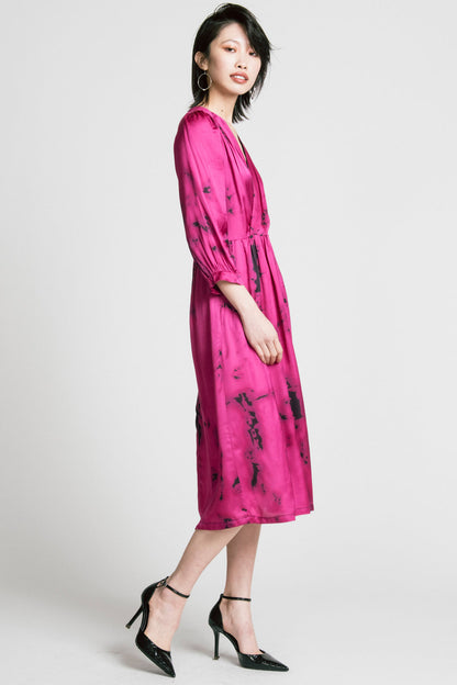 Side view of a woman wearing the Therapy Dress by Allison Wonderland in Pink Print, with a faux wrap front, gathers at the shoulders cuffs and waist, and a full midi-length skirt. She is standing in front of a white background. 