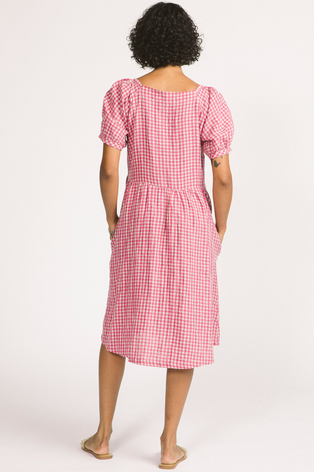 Verity Dress by Allison Wonderland, Pink Gingham, back view, V-neck, slightly puffed short sleeves with gathers at cuffs, gathers at front back and sides, below the knee length, pockets, 100% linen, sizes 2-12, made in Vancouver