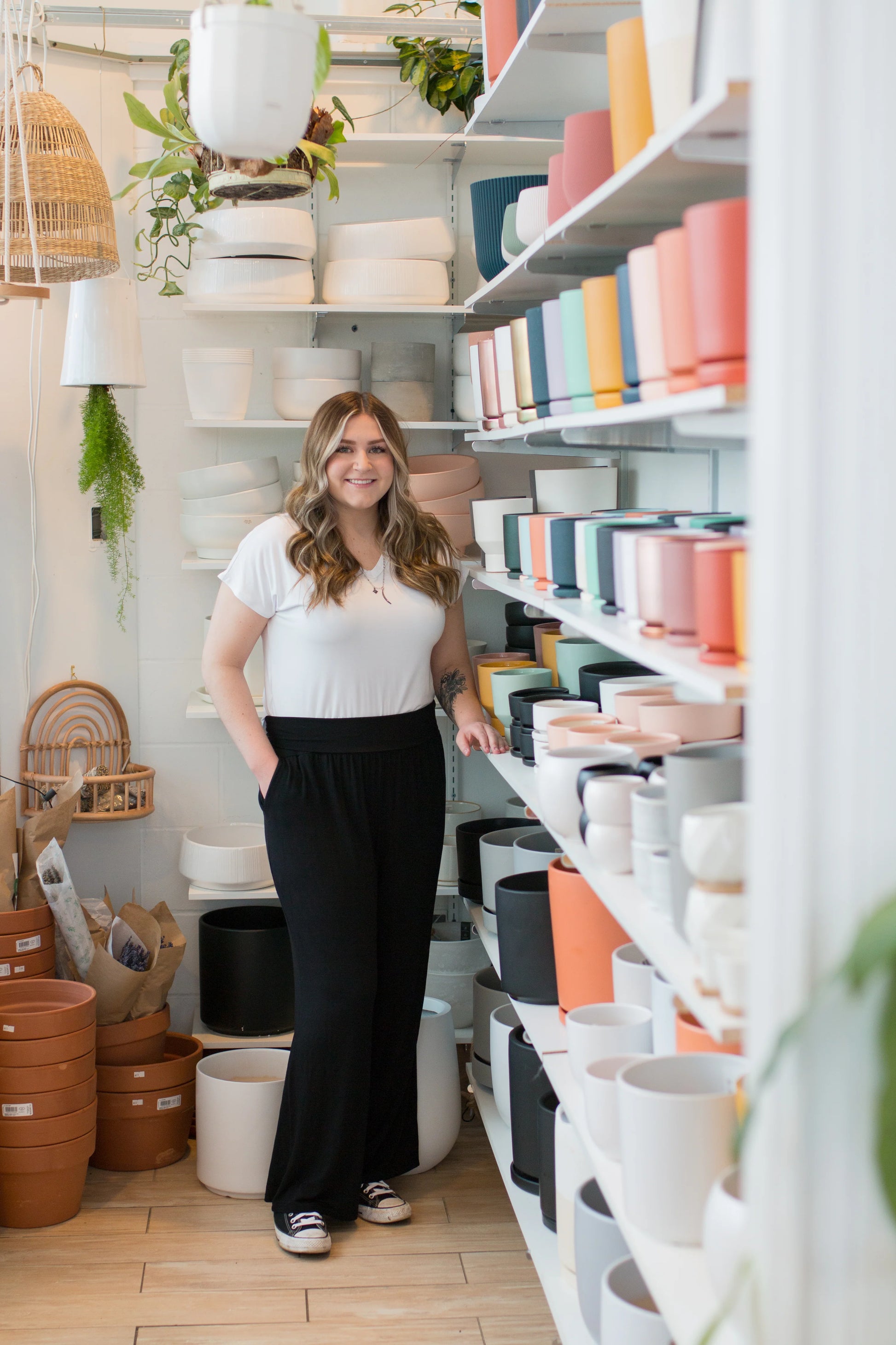 A woman wearing the Bree Wide Leg Pants by Ang Hill in Black, cropped wide-legged pants with a high elastic waist band and deep pockets. She is wearing them with a white t-shirt and standing in a pottery studio. 