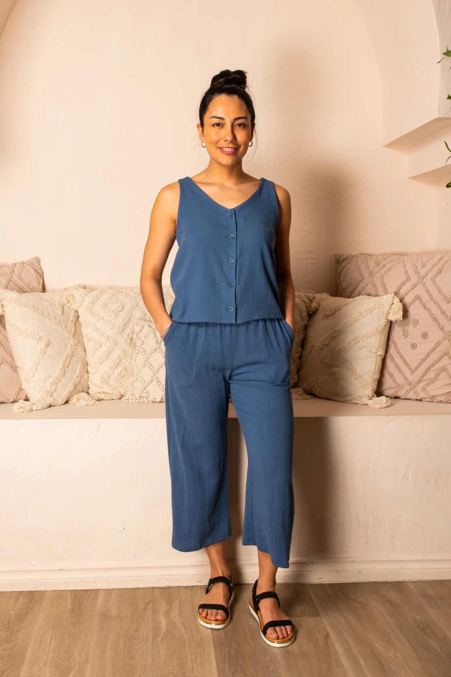Photo of a woman wearing the Serenity Pants by Cherry Bobin in Blue standing in front of a sofa 