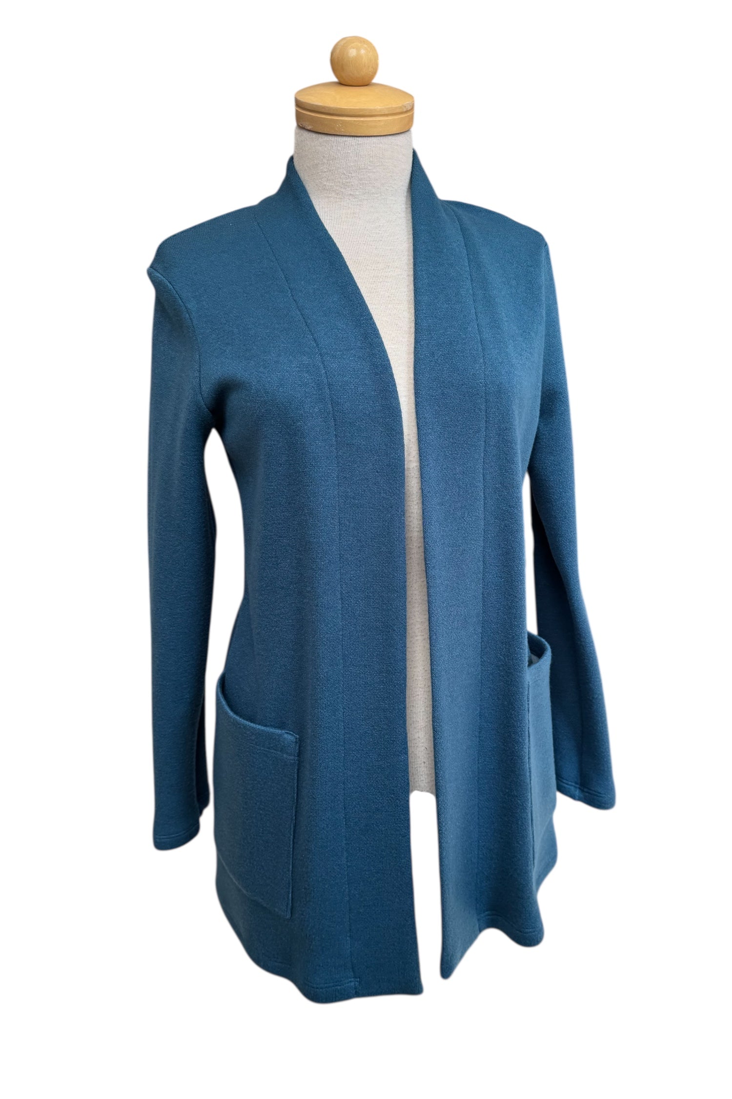 The Penny Cardigan by Compli K in Peacock, a long open knit cardigan with long sleeves and large patch pockets, is shown on a mannequin against a white background.