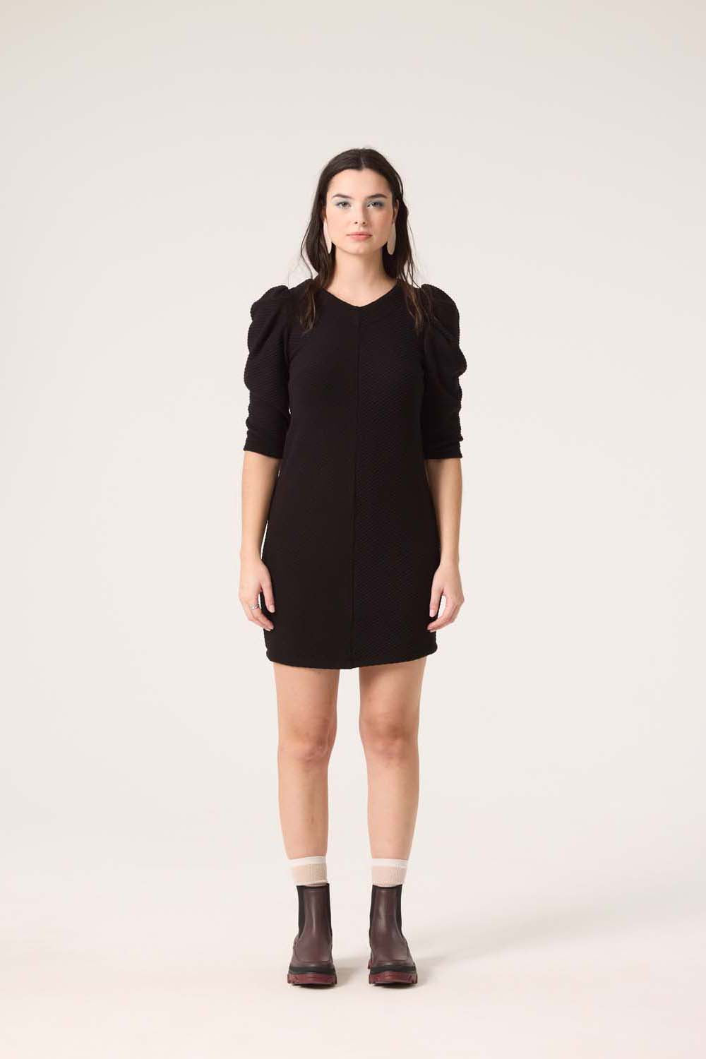 A woman wearing the Celeste Dress by Cokluch in Black, standing in front of a white background