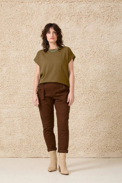 A woman wearing the Ombre Top by Cokluch in Oregano, standing in front of a beige wall