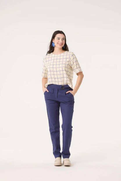 A woman wearing the Sideral Top by Cokluch in Cream Plaid with blue pants, standing in front of a white background 