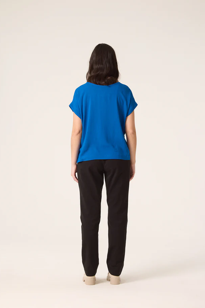 Back view of a woman wearing the Fuzzy Top by Cokluch in Colbalt with black pants, standing in front of a white background 