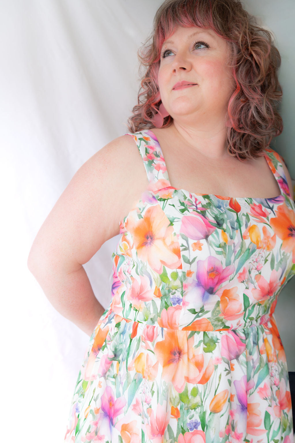A woman wearing the Rue Floral Dress by Compli K, a midi-length tank dress with wide straps, a square neckline, a gathered waist and a full skirt. She is shown against a white background.