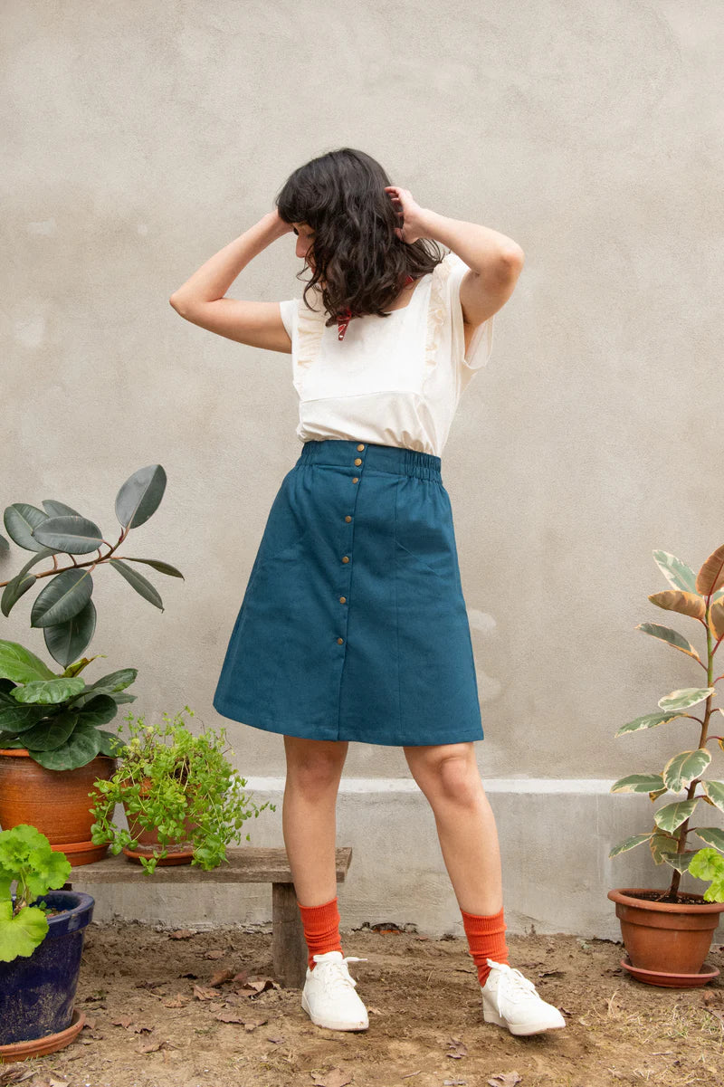 Chrysanthème Skirt by Kazak, Teal, knee-length, A-line, elastic at sides and back of waist, brass buttons up the front, two large pockets, eco-fabric, linen, rayon, sizes XS to XL, made in Montreal 