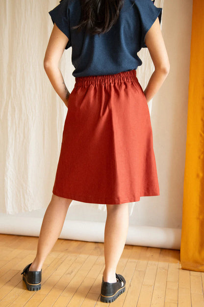 Chrysanthème Skirt by Kazak, Sashimi, back view, knee-length, A-line, elastic at sides and back of waist, brass buttons up the front, two large pockets, eco-fabric, linen, rayon, sizes XS to XL, made in Montreal 