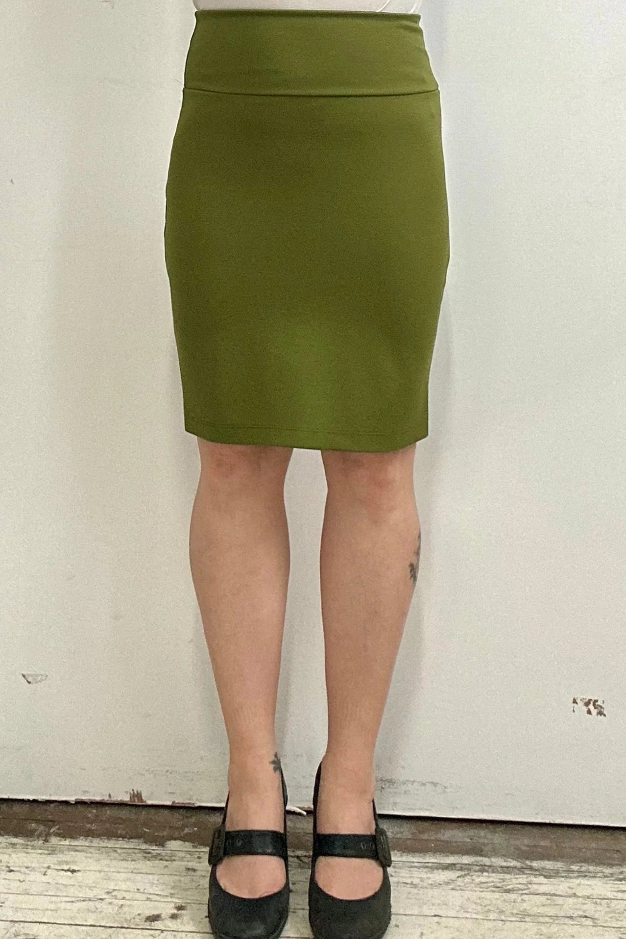 Waist down view of a woman wearing the Veneto Skirt by Kollontai in Granny Smith, a pencil skirt with a wide-pull on waistband that hits above the knee.