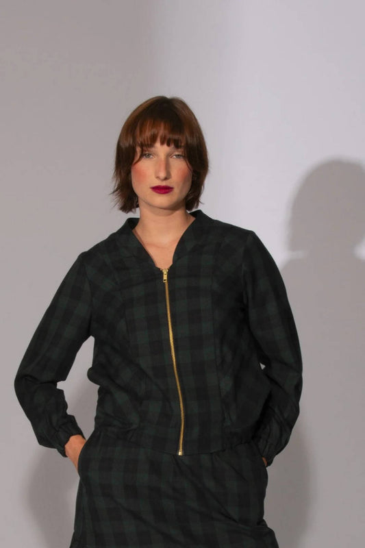 A woman wearing the Eve Lavoie Redrawn Jacket, a tartan bomber jacket, in Black and Forest Tiles.