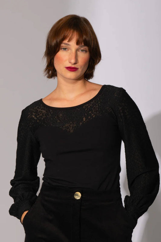 A woman wearing the Spike the Senses Reversible Top by Eve Lavoie in Black Lace, with a sweetheart neckline and puffed sleeves