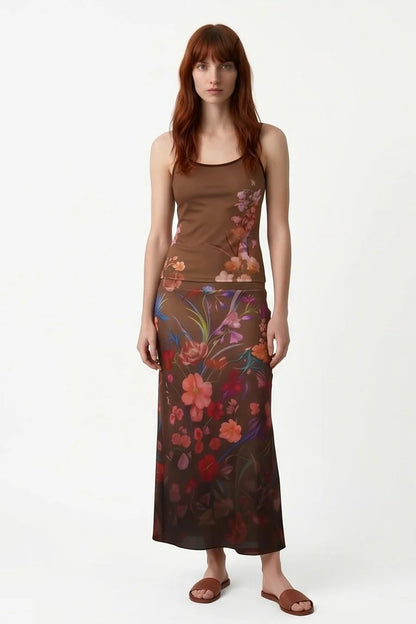 A woman wearing the Charlotte SKirt by Kollontai, a long slim cut brown skirt adorned with a floral pattern. She is wearing it the matching Morganne Top against a white background