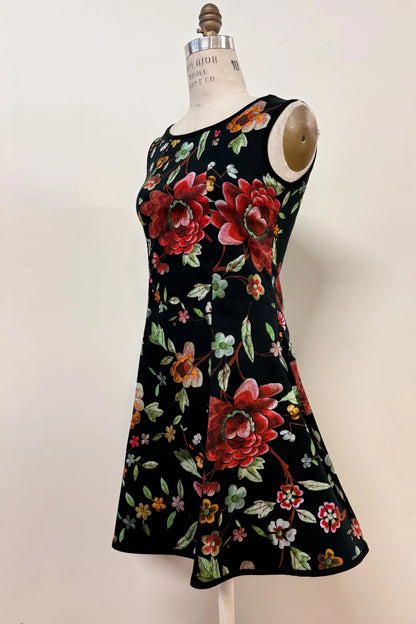 The Silba Dress FW26/27 by Kollontai in Black Floral, a short sleeveless dress with princess seams and an above the knee skirt, is shown on a mannequin against a white background. 