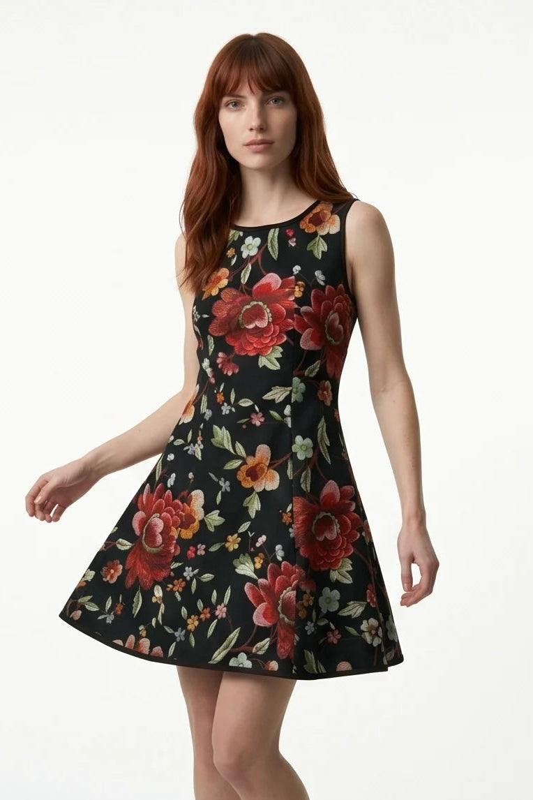 A woman wearing the Silba Dress FW26/27 by Kollontai in Black Floral, a short sleeveless dress with princess seams and an above the knee skirt. She is standing against a white background. 