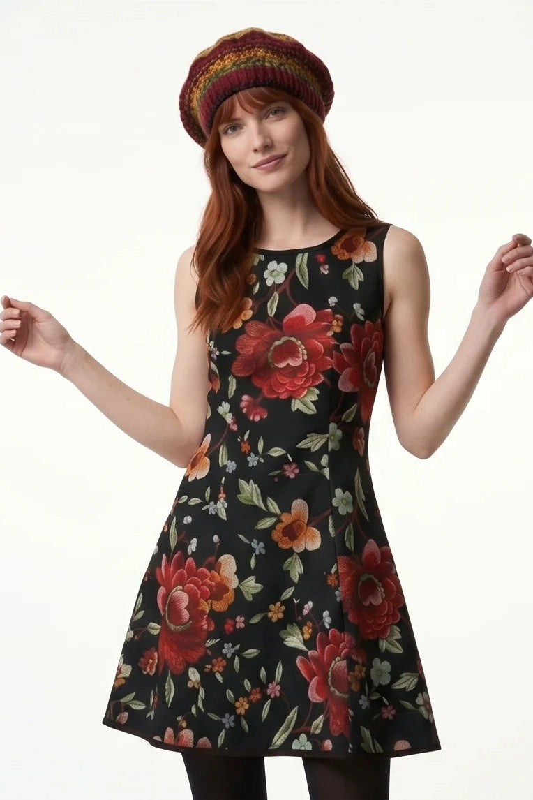 A woman wearing the Silba Dress FW26/27 by Kollontai in Black Floral, a short sleeveless dress with princess seams and an above the knee skirt. She is standing against a white background. 