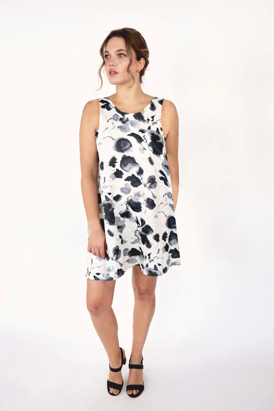 A woman wearing the Amina Linen Sleeveless Dress by Korelli in printed linen, standing in front of a white background 