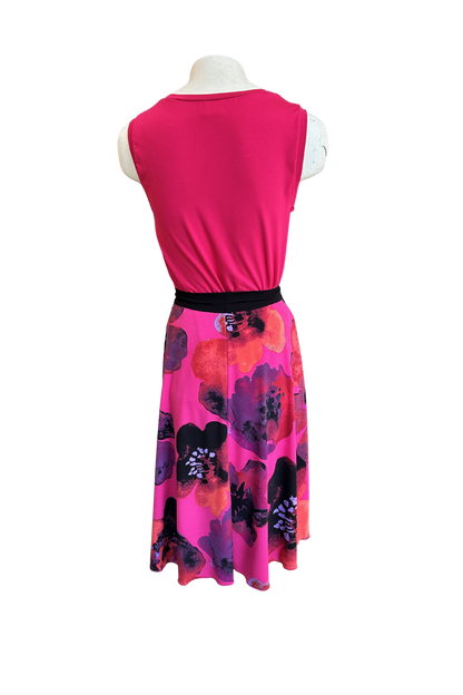 A back view of the Folie Skirt in Fuchsia Print by Slak is shown on a mannequin with the Neon Camisole in Fuchsia against a white background. It's a below-the-knee A-line skirt with a contrast pull-on waistband. 