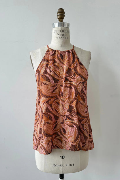 The Semira Camisole by Kollontai in Cinnamon print, a lightweight top with an adjustable halter neck and a loose fit, is shown on a mannequin in front of a white background. 