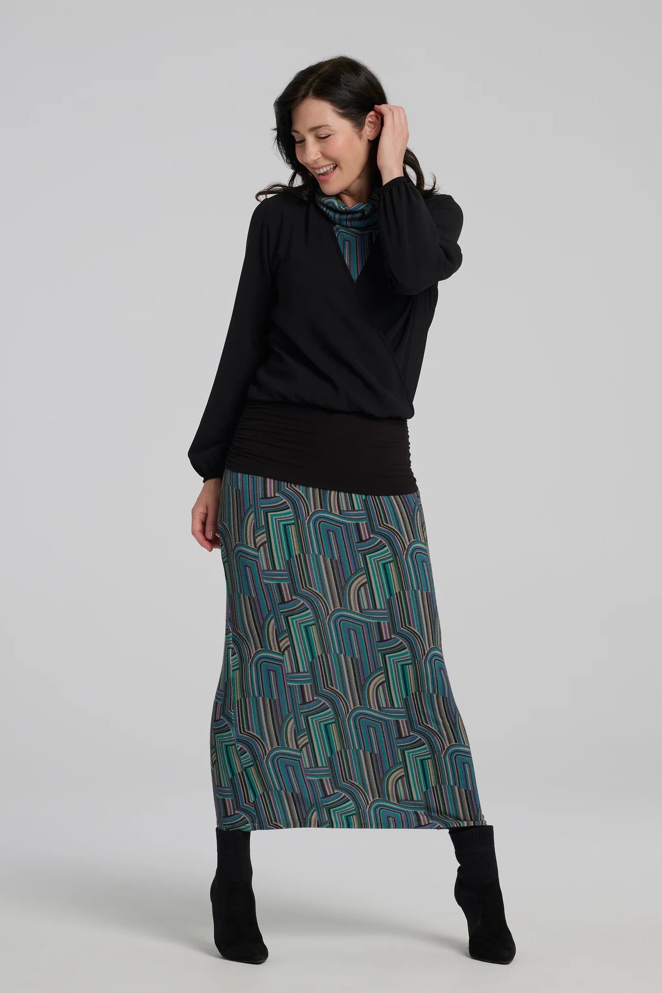 A woman wearing the Ysia Dress by Kollontai, a sleeveless turtleneck dress with a geometric pattern. She is standing in front of a white background. 