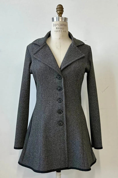 The Henderson Jacket by Kollontai in Charcoal tweed, with a fitted A-line shape that flares from the waist, a classic collar, and buttons down the front, shown on a mannequin in front of a white background. 