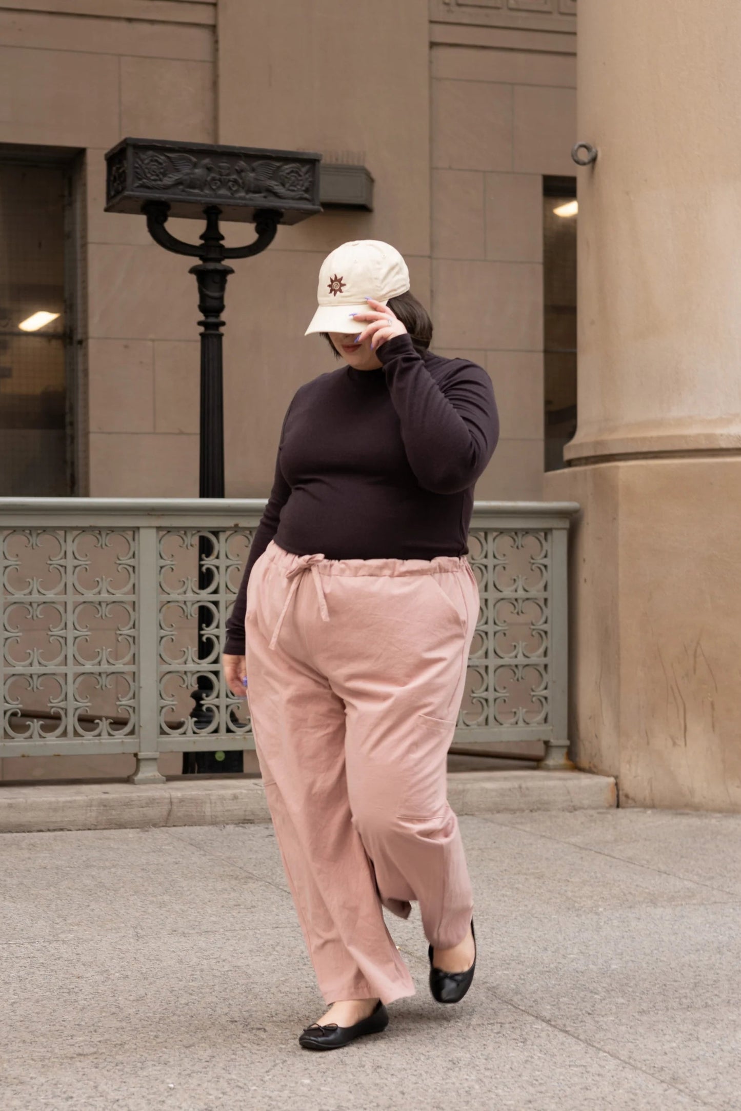 A woman wearing the Essential Turtleneck by Lights of All in Coffee with brown pants, standing on the street.