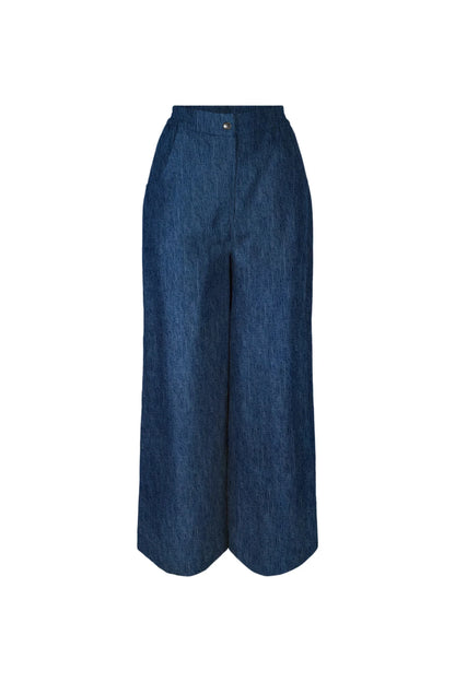 The Matisse Trousers by Melow in Denim, full length wide leg pants with a zipper front and a high waist with elastic at the back and side and back patch pockets, are shown against a white background. 