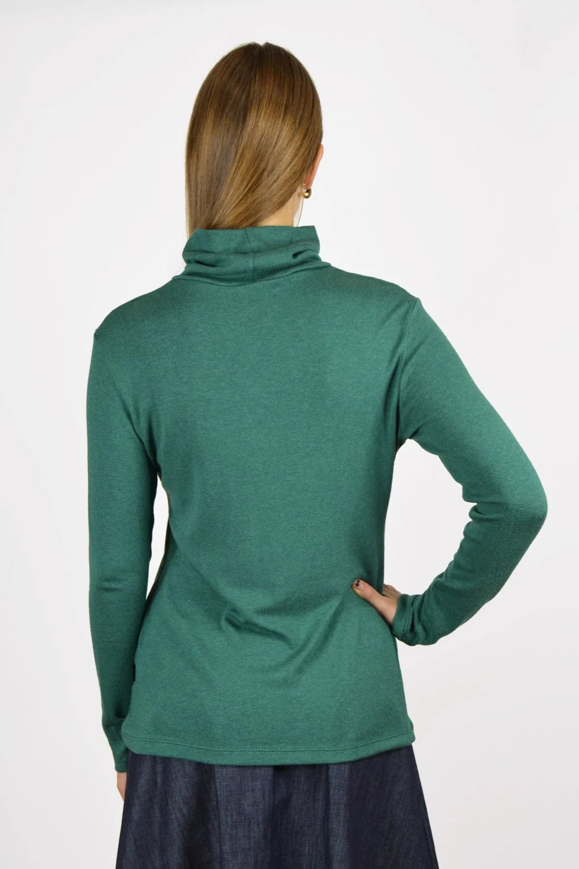 Back view of a woman wearing the Gatineau Turtleneck by Message Factory in Green, a classic turtleneck in a bamboo and cotton blend, with an orange plaid shirt. She's standing in front of a white background. 