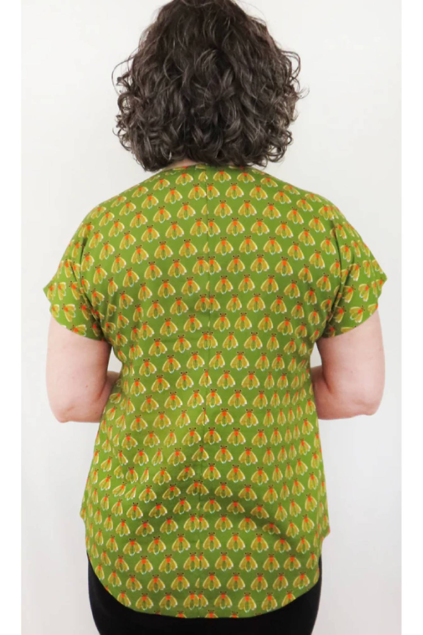 Back view of a woman wearing the Bea Blouse by Mandala in Fly Kiwi print, in front of a white background 