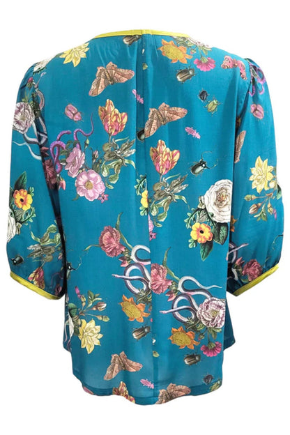 The back of the Lydia Creeper Blouse by Mandala in Bayou is shown in front of a white background. It features a vintage floral print with snakes and insects, with a jewel neck, puffed 3/4 sleeves, and a scooped hem. 