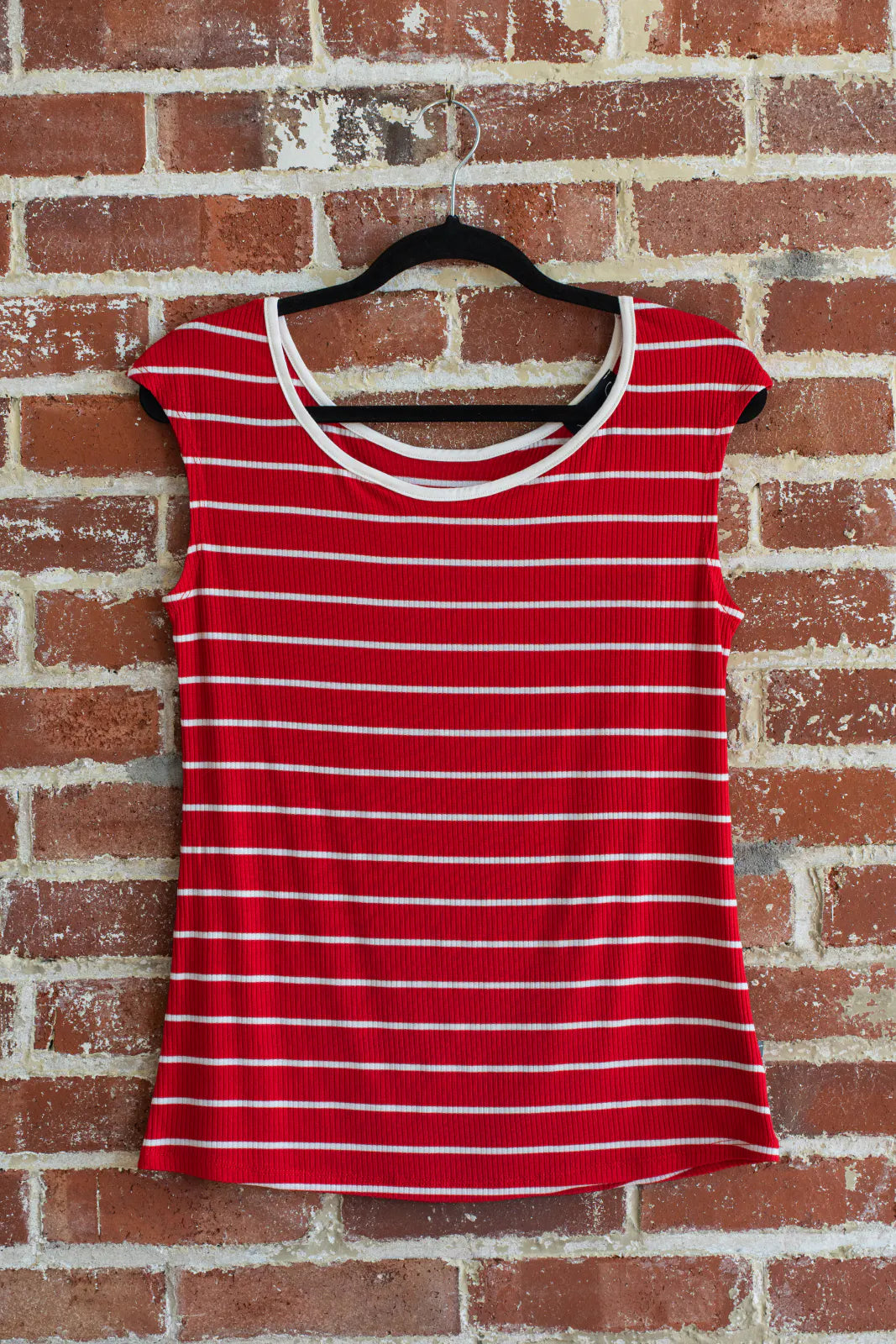 The Sol Top from Marie C in Red Stripe, a reversible cap sleeve tee, is shown hanging vertically in front of a brick wall.