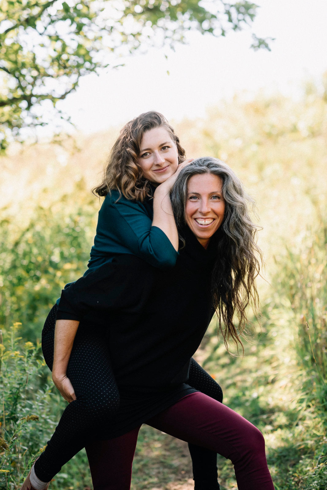 Three women wearing the BeAAA Sweater by Marie C in Everglade and Black, standing in a forest.