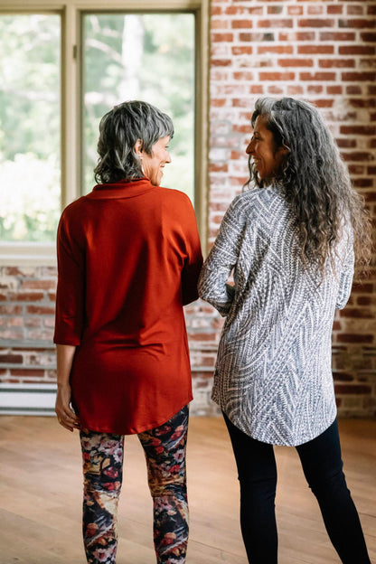 Back view of a woman wearing the Juliana Tunic by Marie C in Navy Print and a woman wearing Juliana Tunic by Marie C in Rust, standing in front of a brick wall 