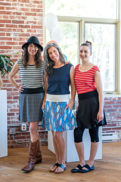 Three women wearing the Soleil Skirt by Marie C, with Sol Tops, standing indoors at a party. 
